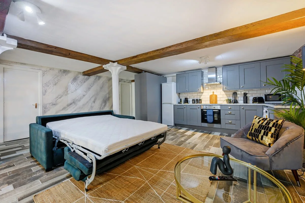 Un estudio combina una cama, una zona de estar y una cocina al fondo.