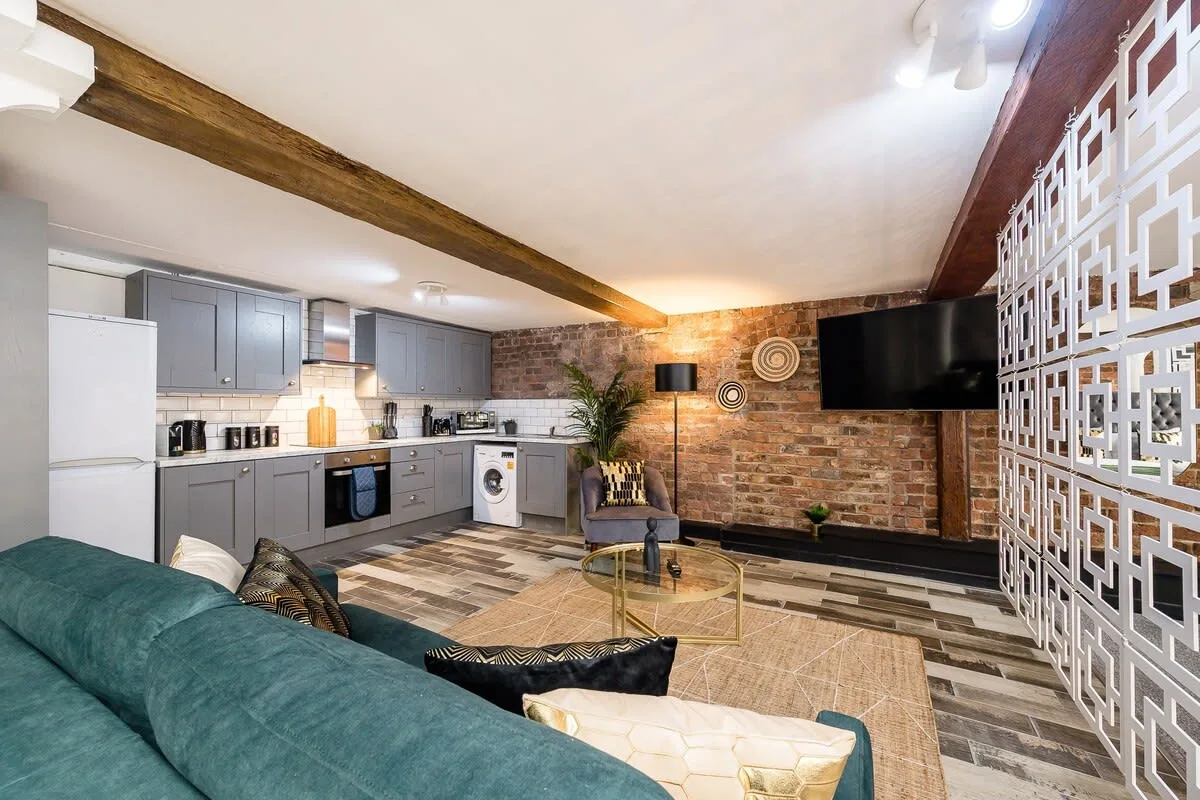 Una sala de estar con televisor, asientos y una cocina contigua.