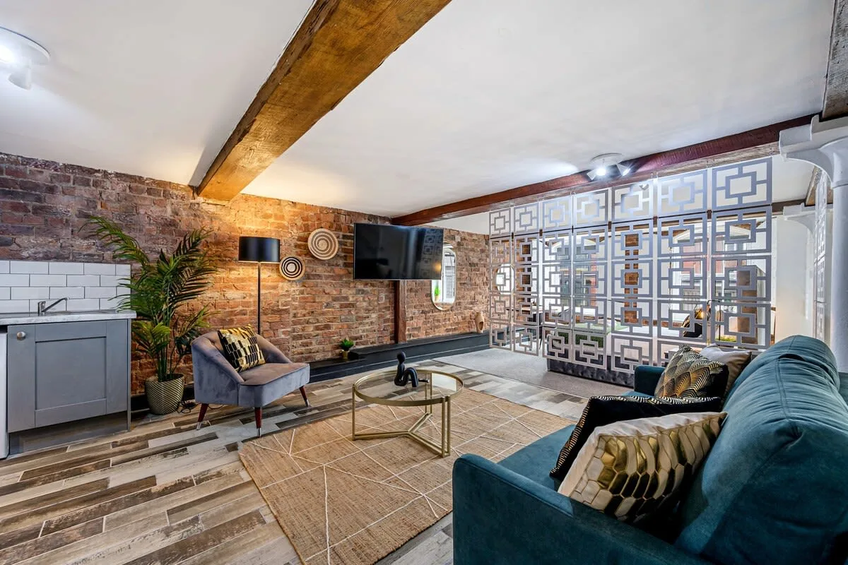 Sala de estar con asientos, un televisor y un panel decorativo estampado.
