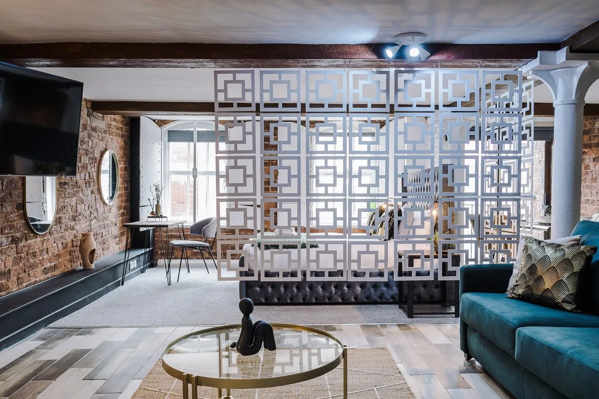 Sala de estar con asientos y un separador geométrico decorativo.