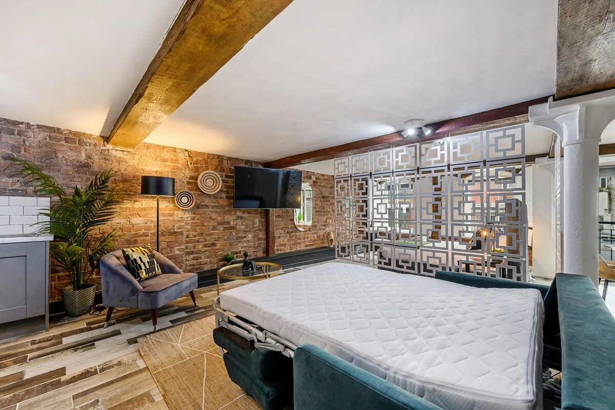 Un estudio con una cama grande, asientos y un biombo decorativo.