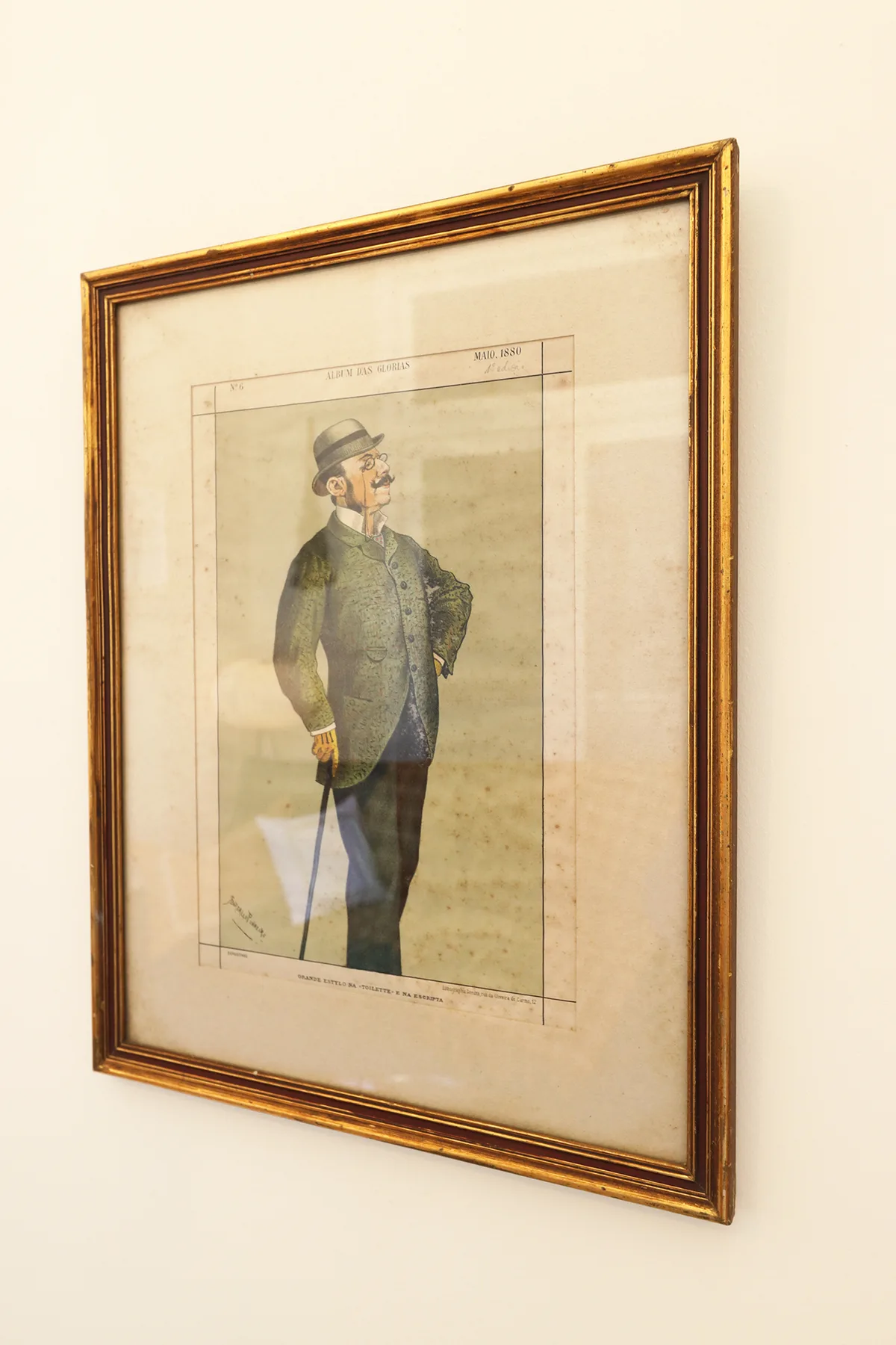 Una lámina enmarcada de una figura de pie cuelga en una pared clara.
