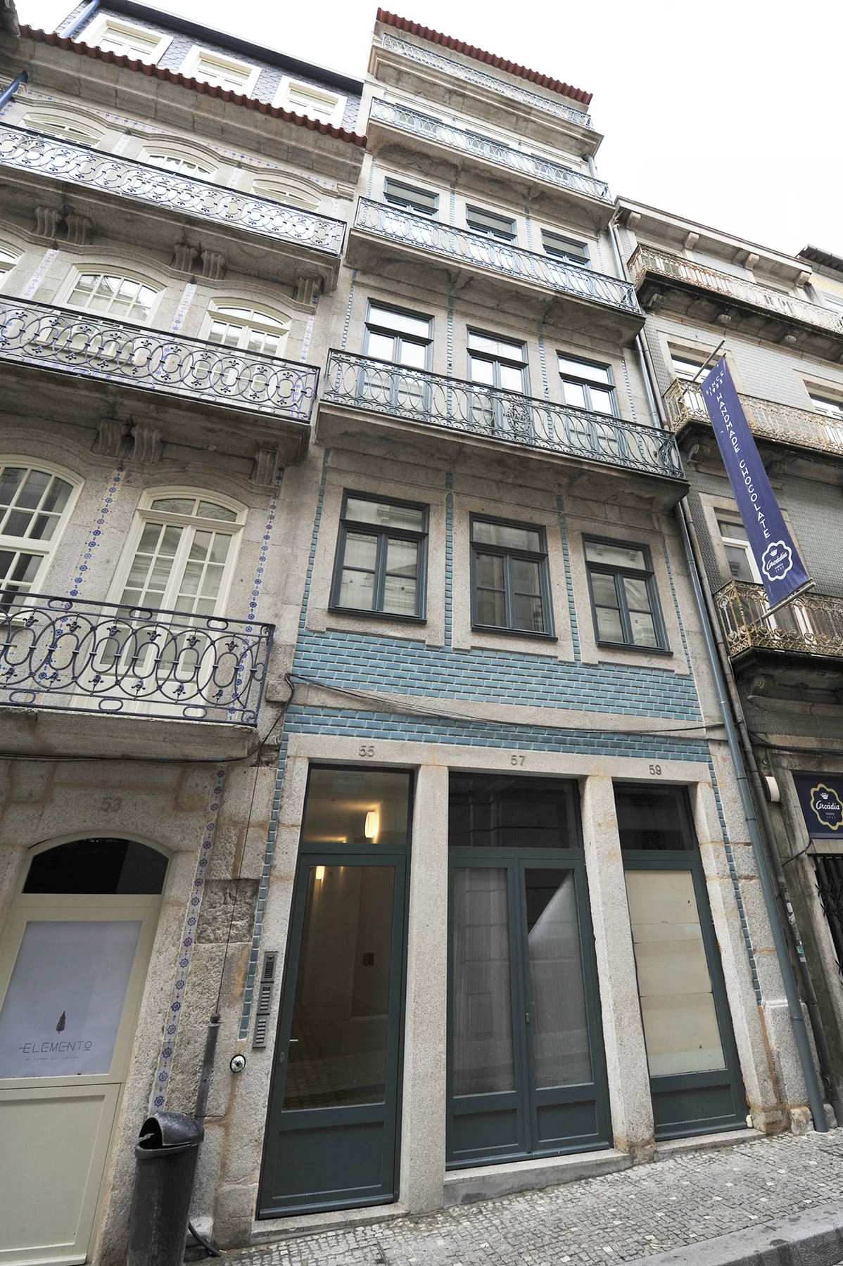Una estrecha fachada de varias plantas con balcones y entradas a nivel de calle.