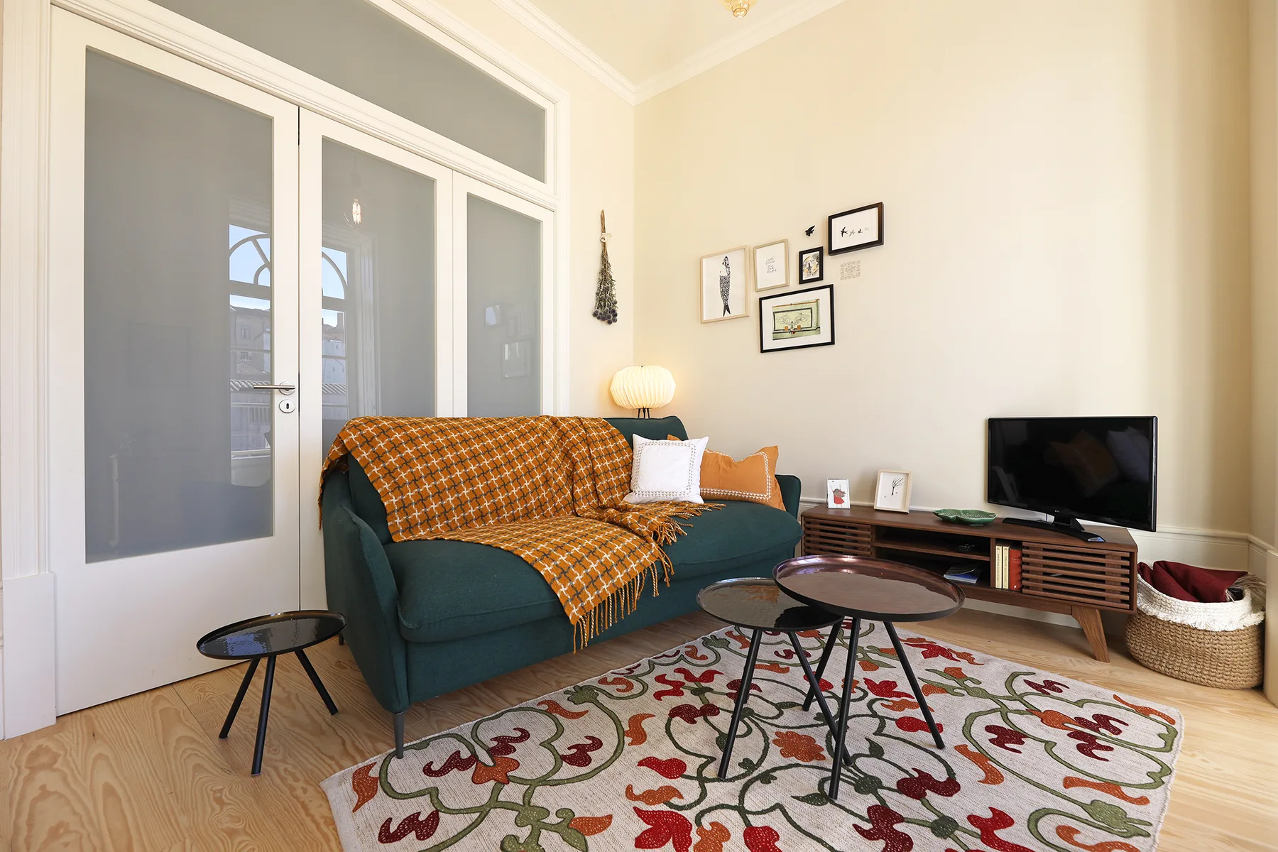 Sala de estar con asientos, un televisor y una alfombra estampada.