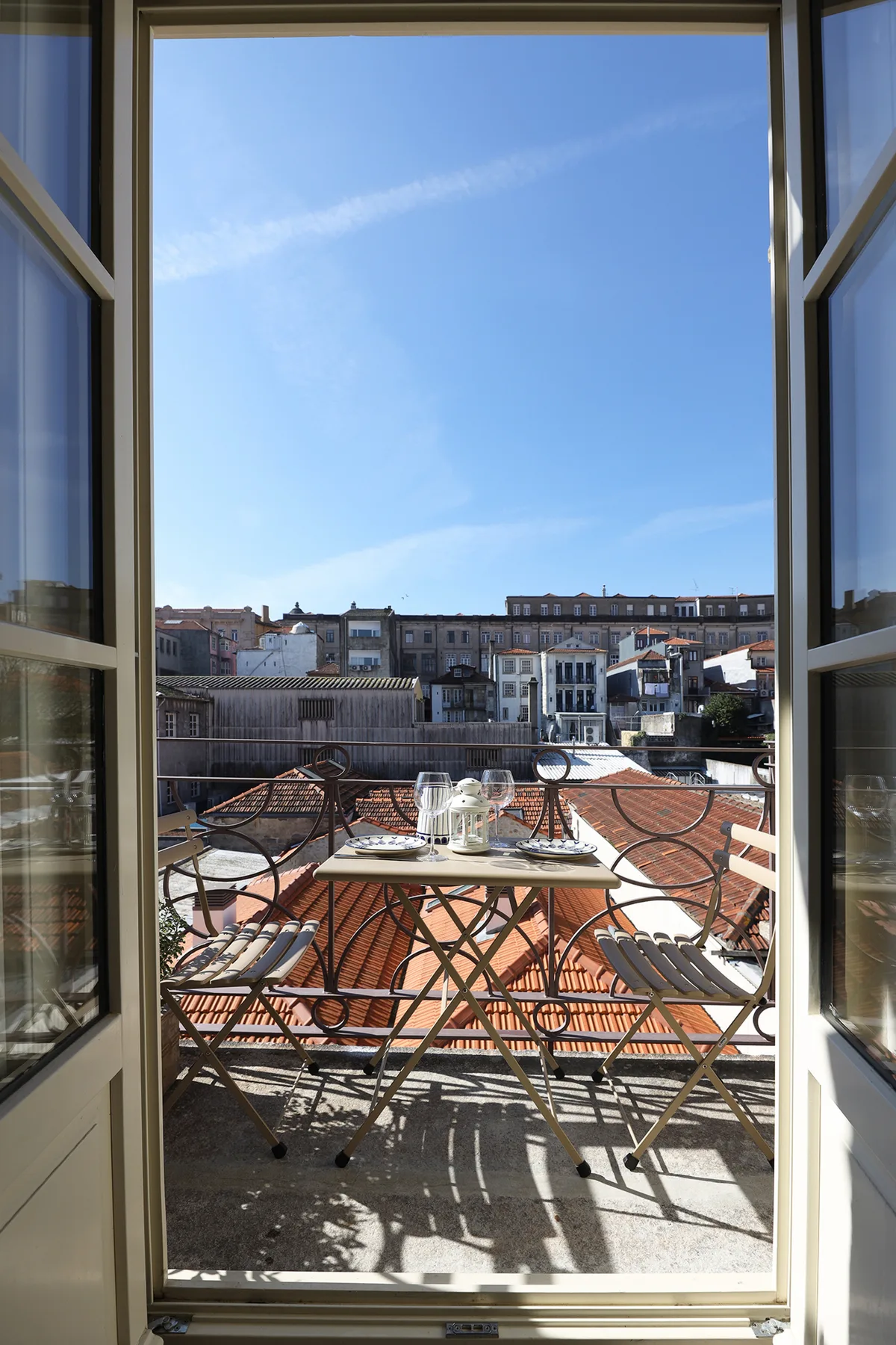 Una pequeña terraza con asientos al aire libre da a tejados y edificios cercanos.