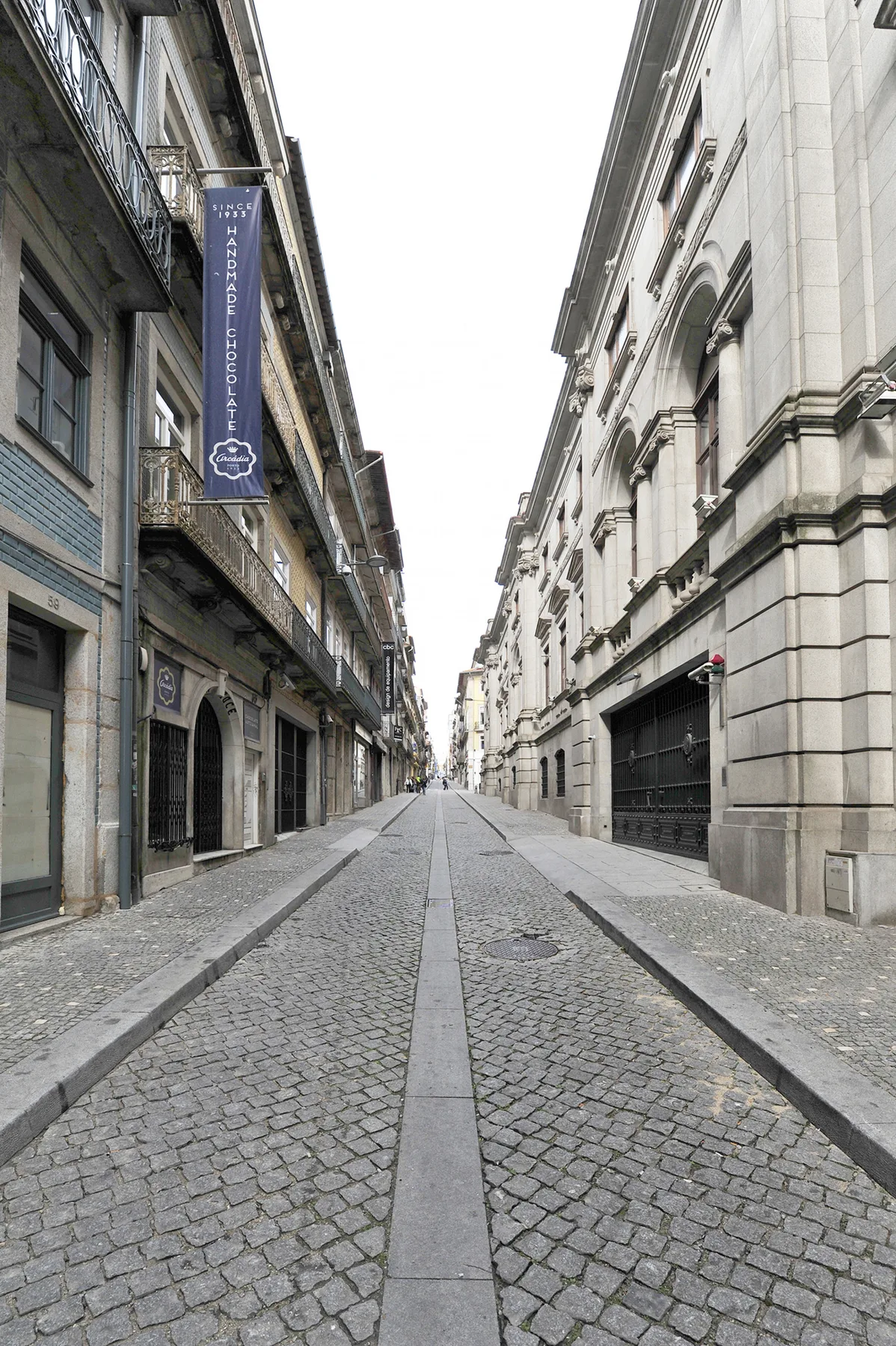 Una calle empedrada discurre entre edificios altos con fachadas de piedra.