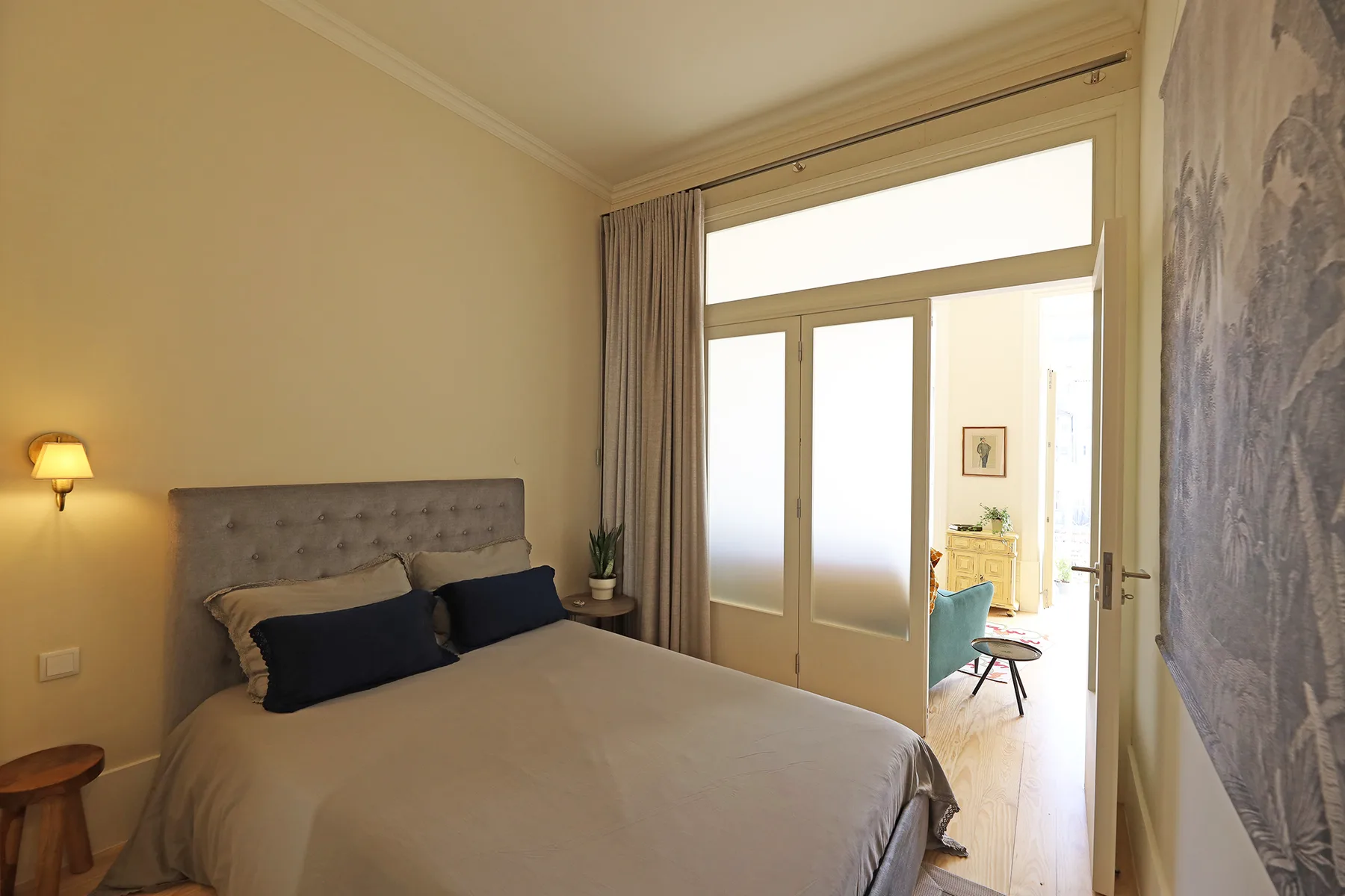 Un dormitorio con una cama doble junto a puertas de vidrio esmerilado que dan a una zona de estar.