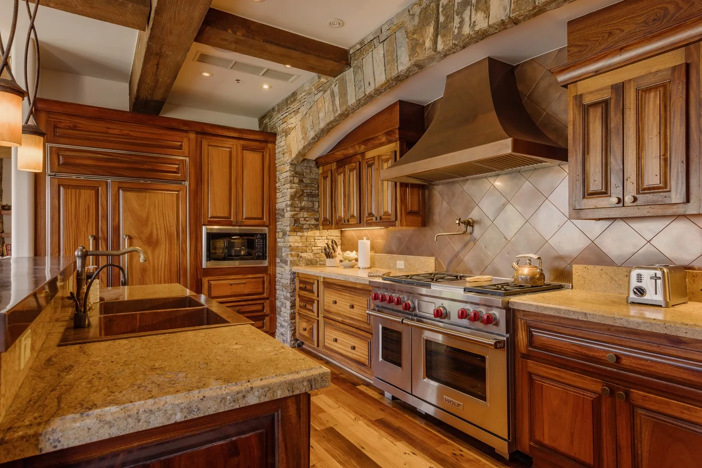 A warm wood-paneled kitchen with a central island and large cooking range.