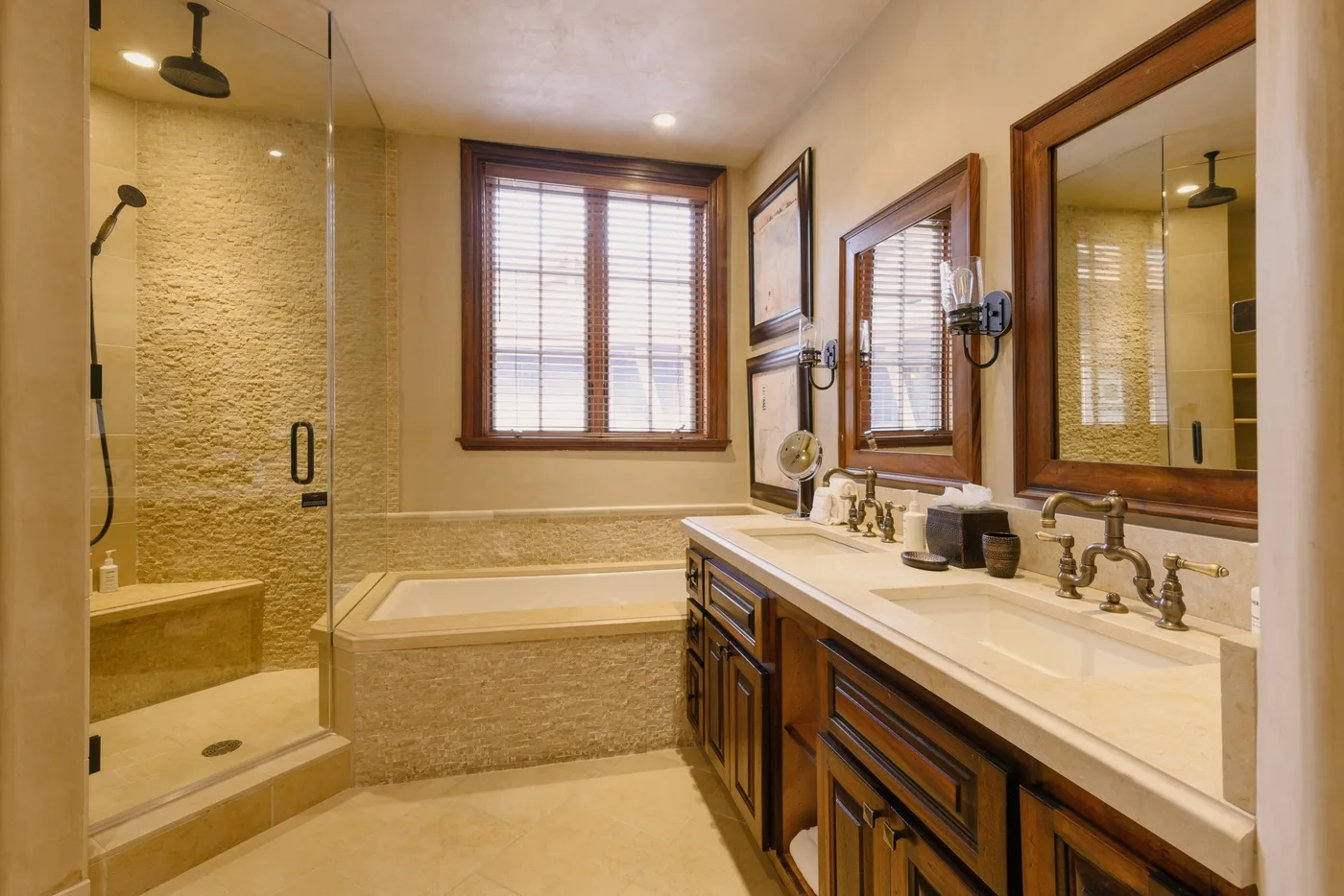 A bathroom with a glass-enclosed shower, bathtub, and long vanity.