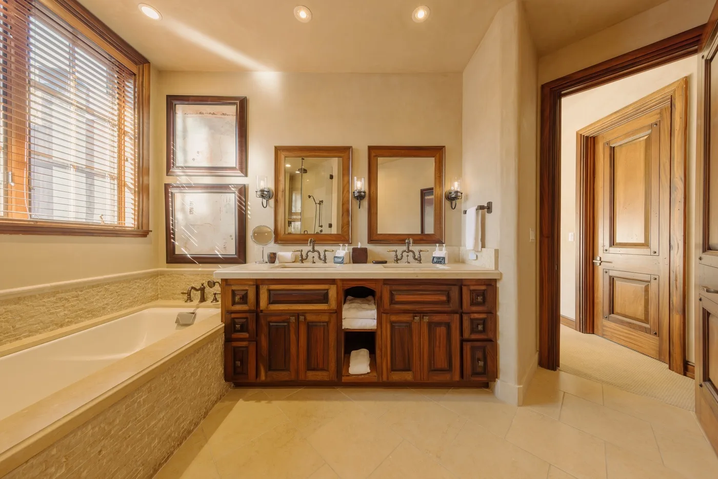 A spacious bathroom with a double vanity, bathtub, and window blinds.
