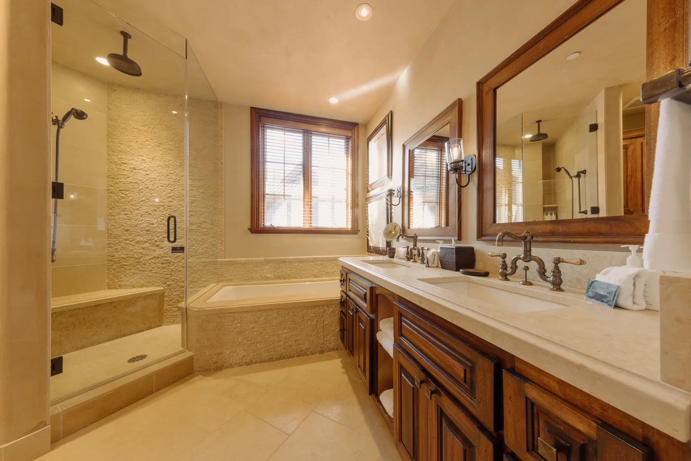 A bathroom with a glass shower, a bathtub, and a long vanity.