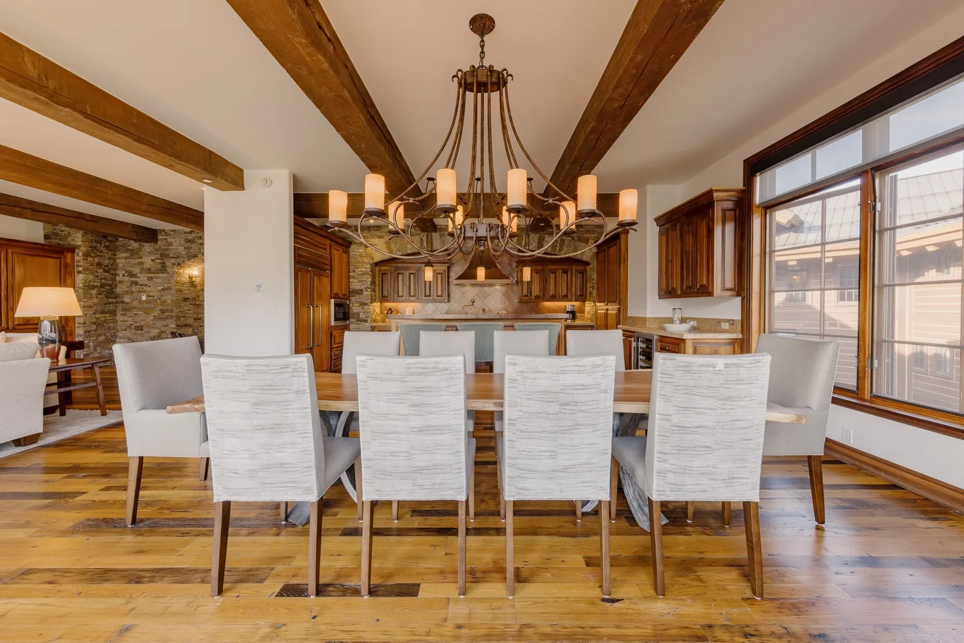 A dining area with a long table, seating, and exposed wooden ceiling beams.