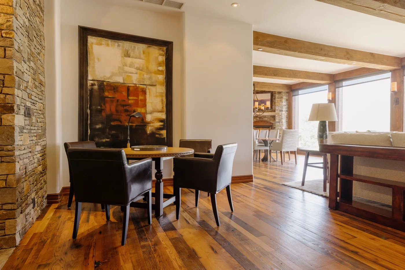 A dining area with dark seating and framed artwork beside a bright living space.