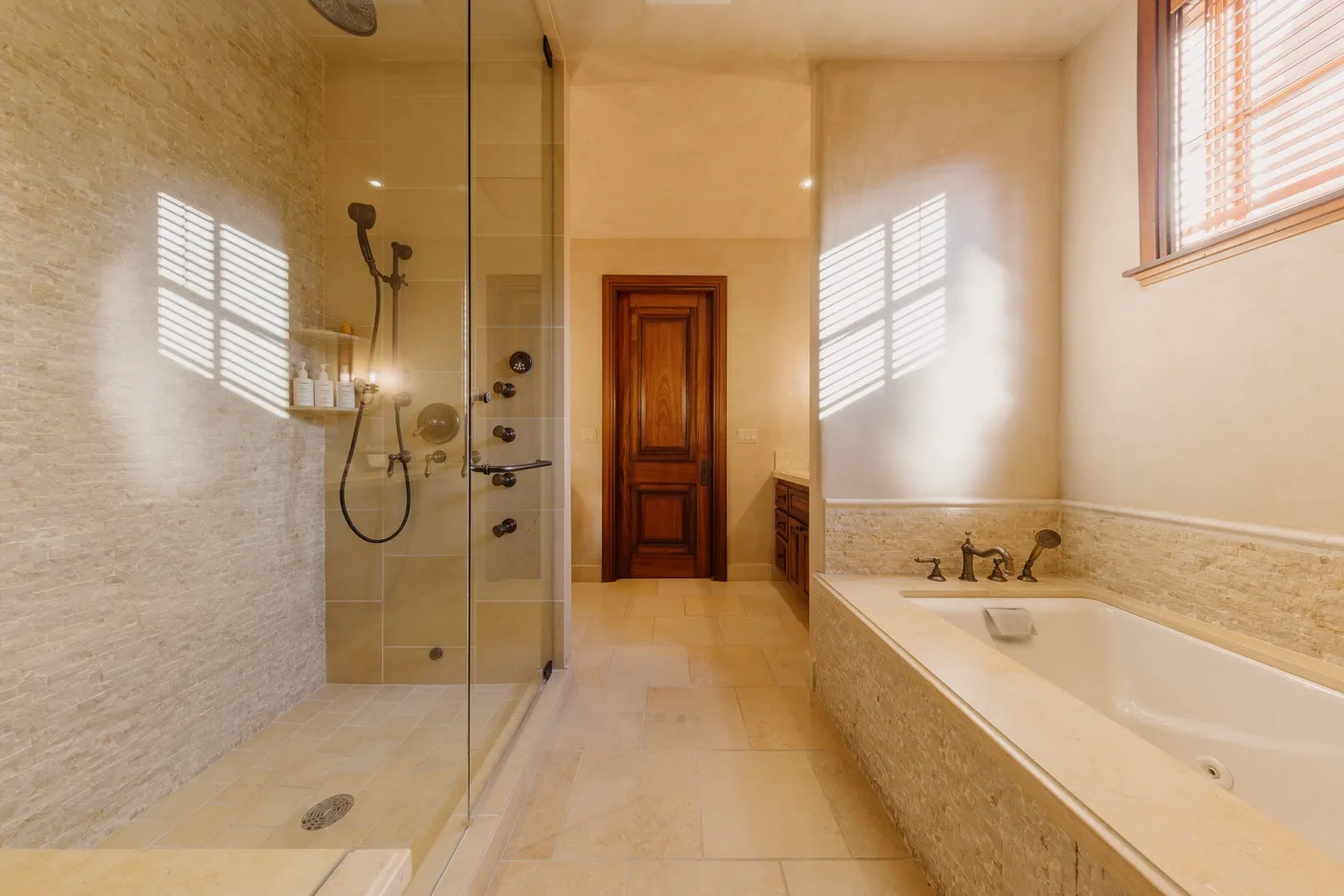 A bright bathroom features a glass shower and a bathtub beside the window.