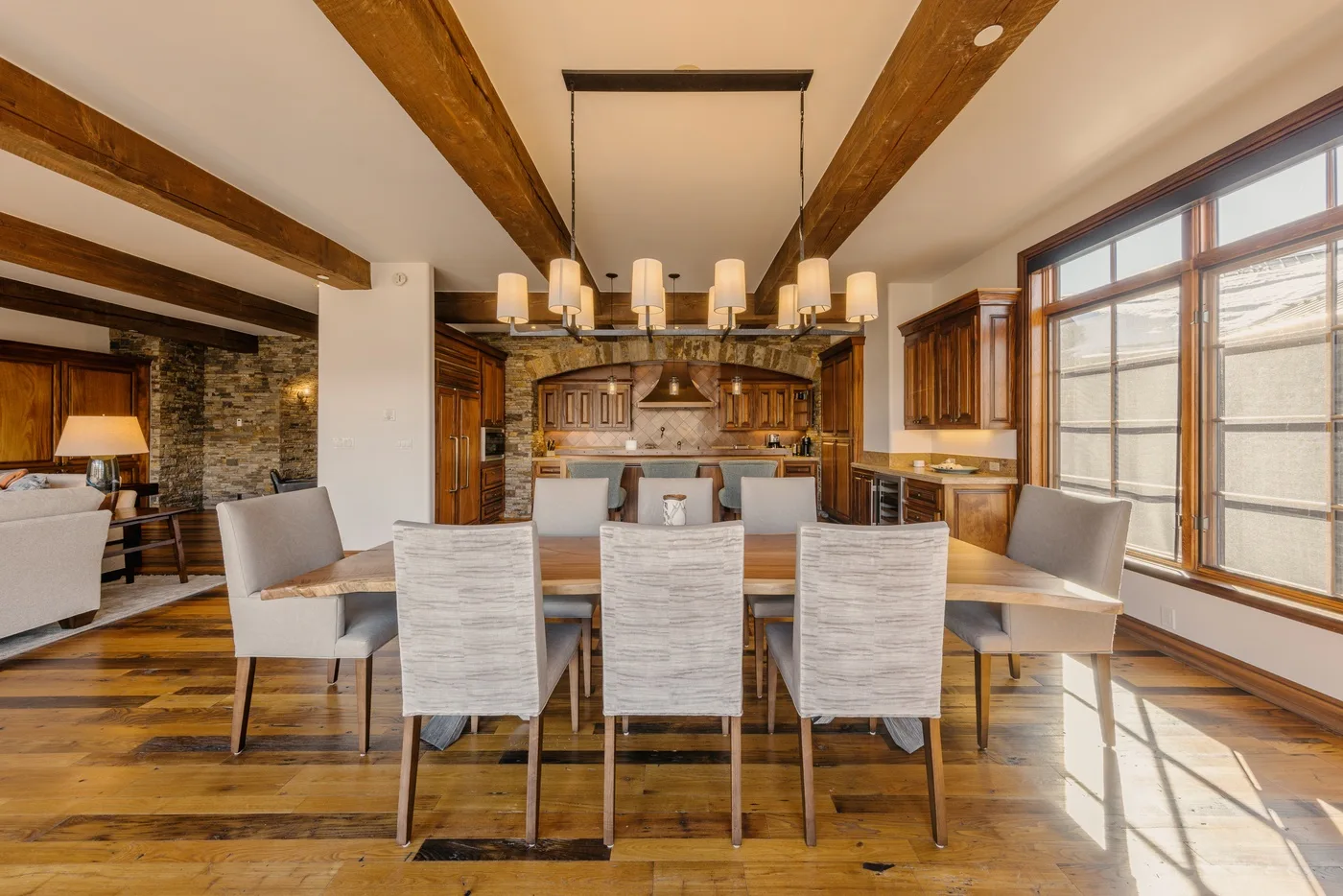 A dining area with a long table beneath exposed wooden ceiling beams.