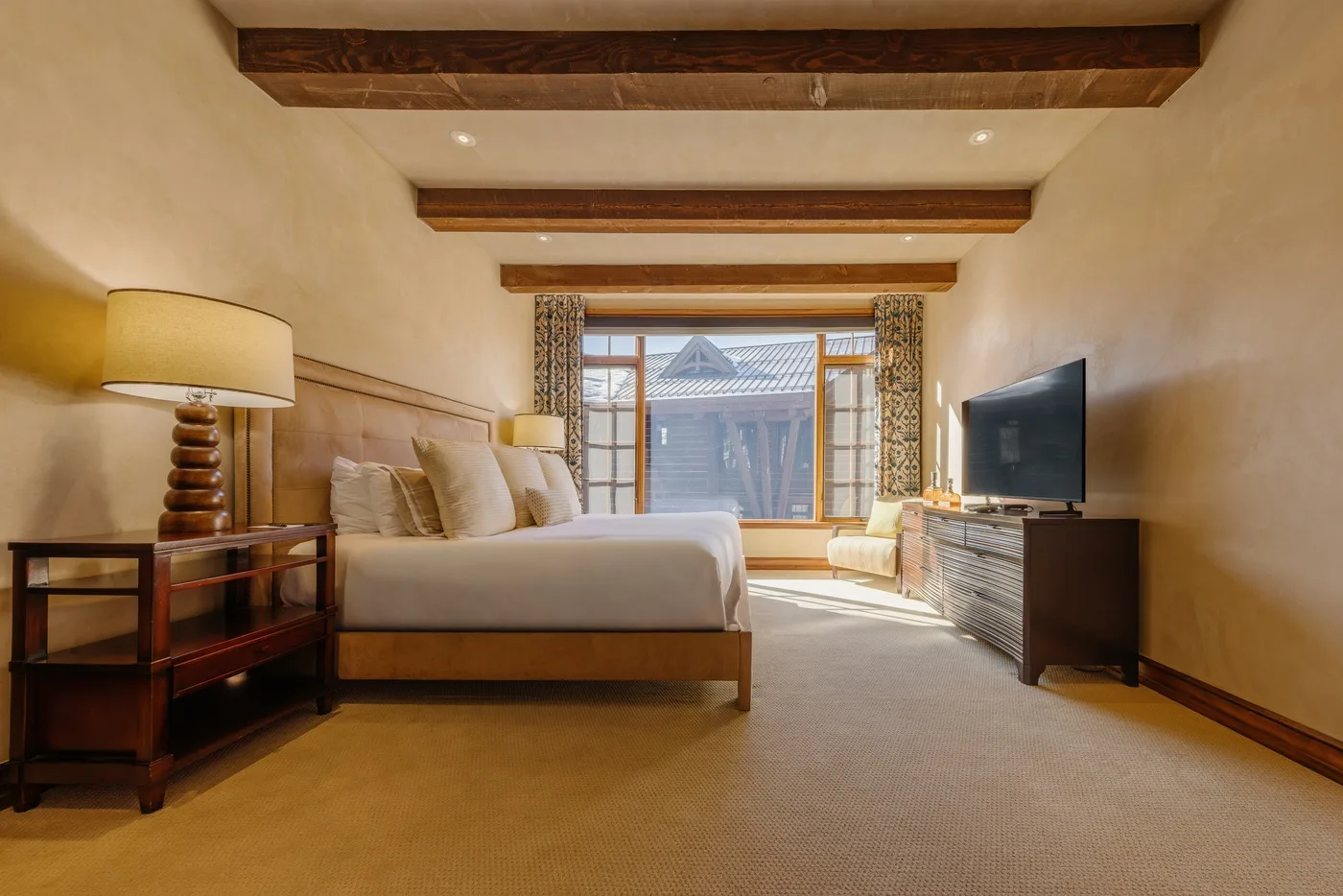 A bedroom with a bed, a television, and a large window.