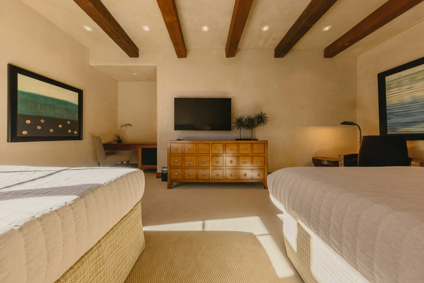 A bedroom with two beds, a television, and a wooden dresser.