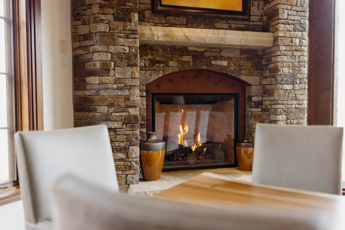 A stone fireplace with a fire burning in a dining area.