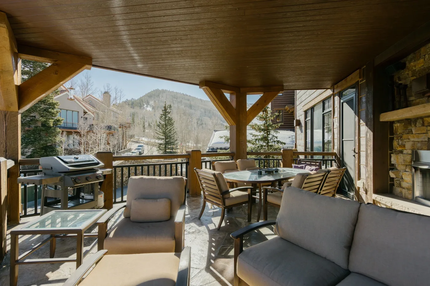 A covered outdoor dining and seating area overlooks a wooded hillside.