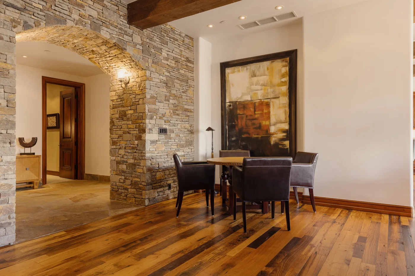 A dining area with a table and seating beside a stone archway.