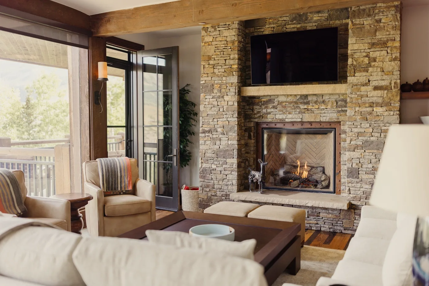 A living room with seating around a coffee table and a stone fireplace.