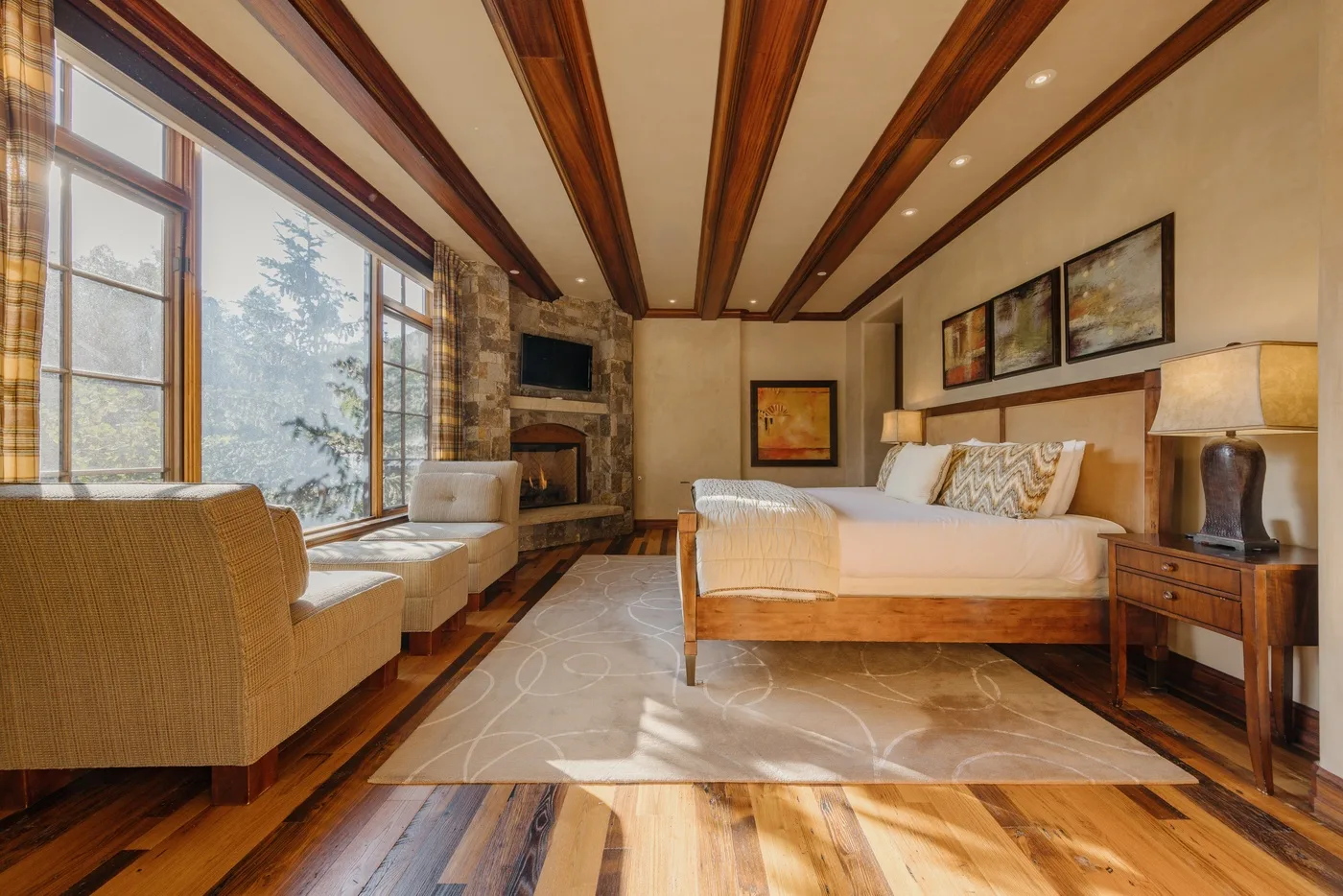A bedroom with a bed, seating, and large windows.