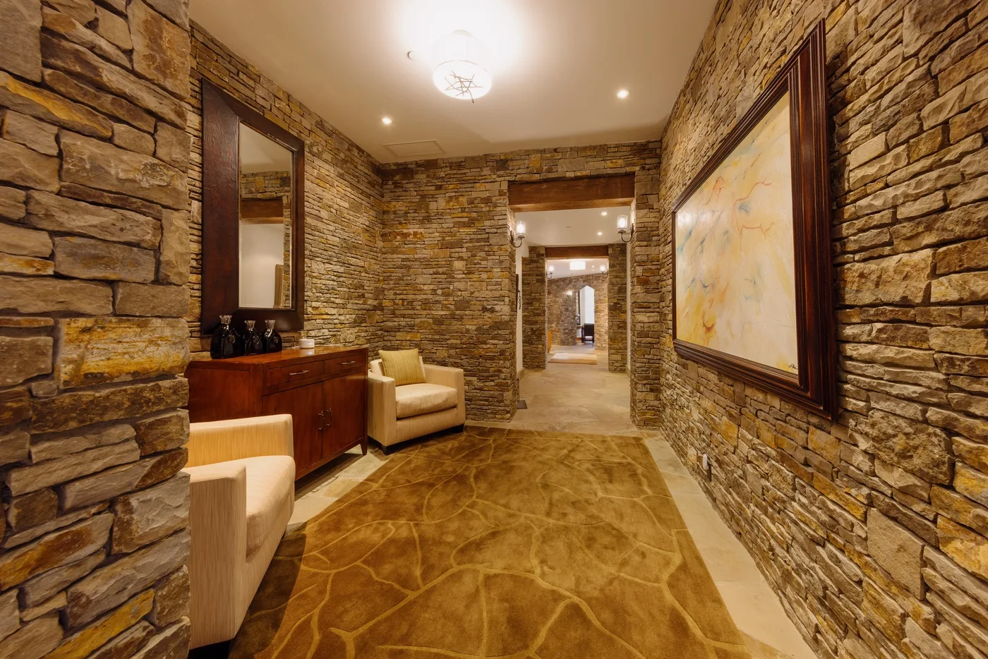 A stone-walled hallway with a patterned floor and framed artwork.