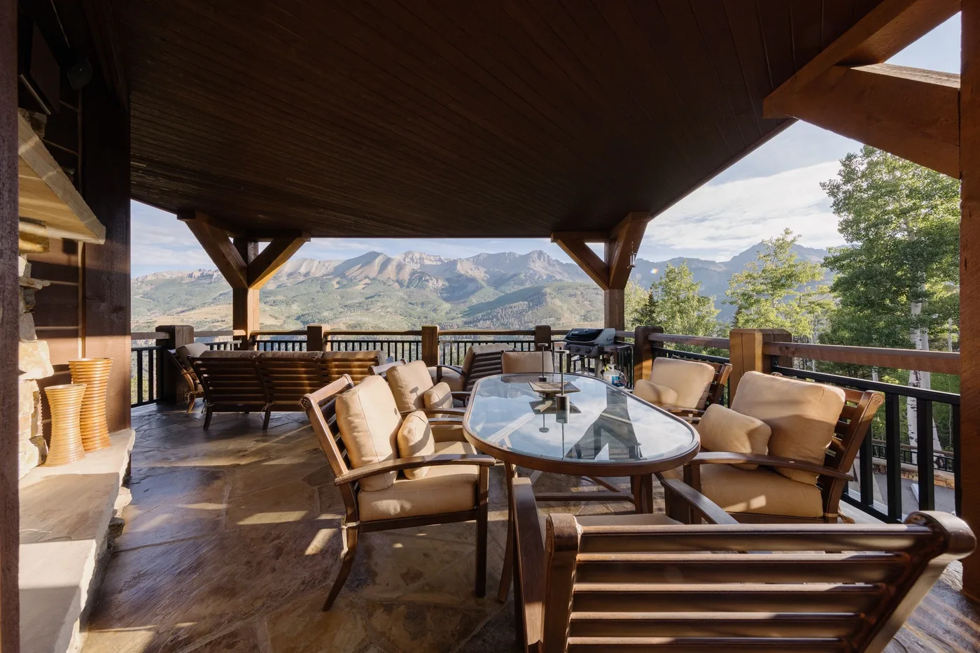 A covered outdoor terrace with cushioned seating and mountain views.