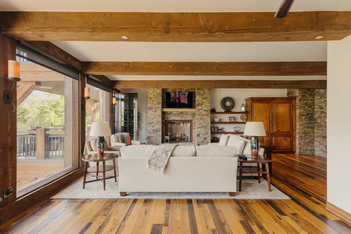 A living room with seating facing a fireplace and large windows.