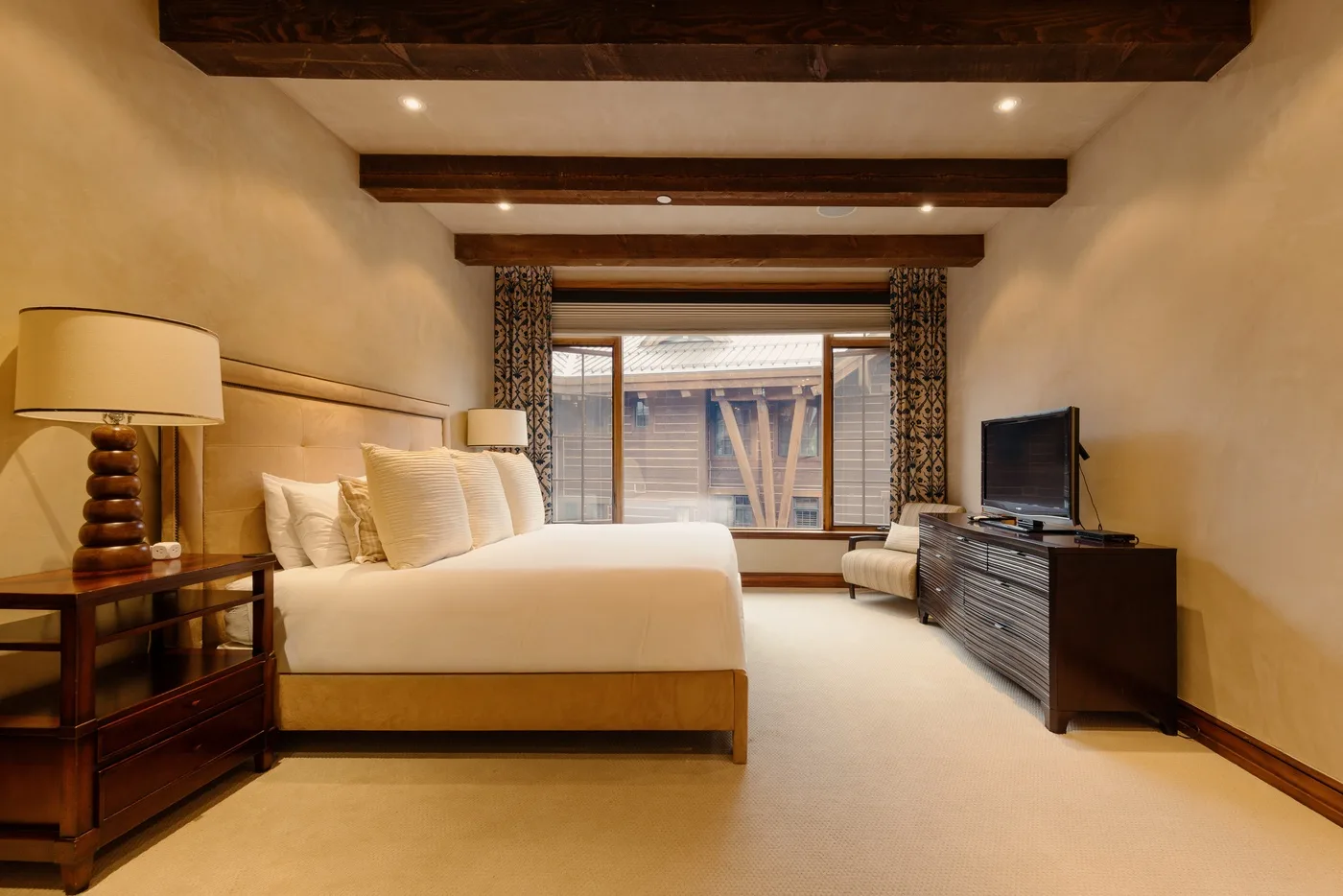 A bedroom with a large bed, bedside lamps, and a television on a dresser.