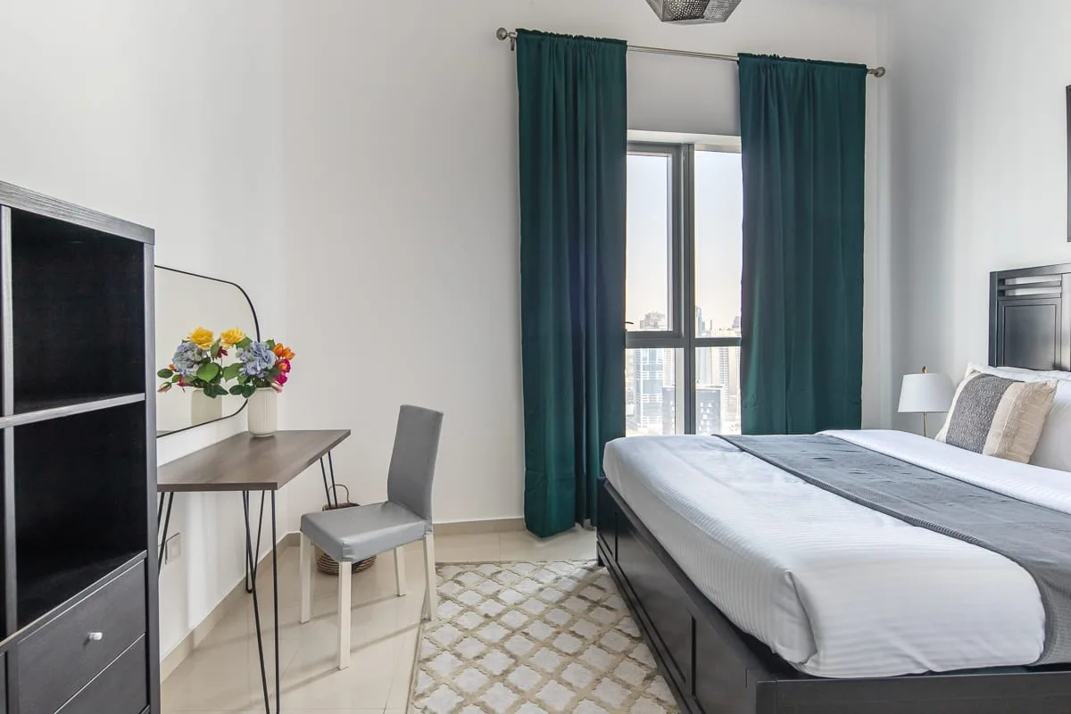 Un dormitorio con una cama grande, una ventana y cortinas verde oscuro.