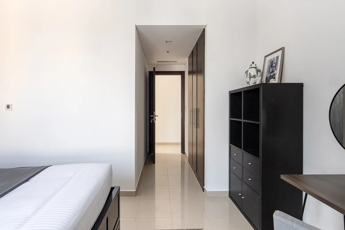 Un dormitorio con una cama junto a un pasillo y un armario oscuro.