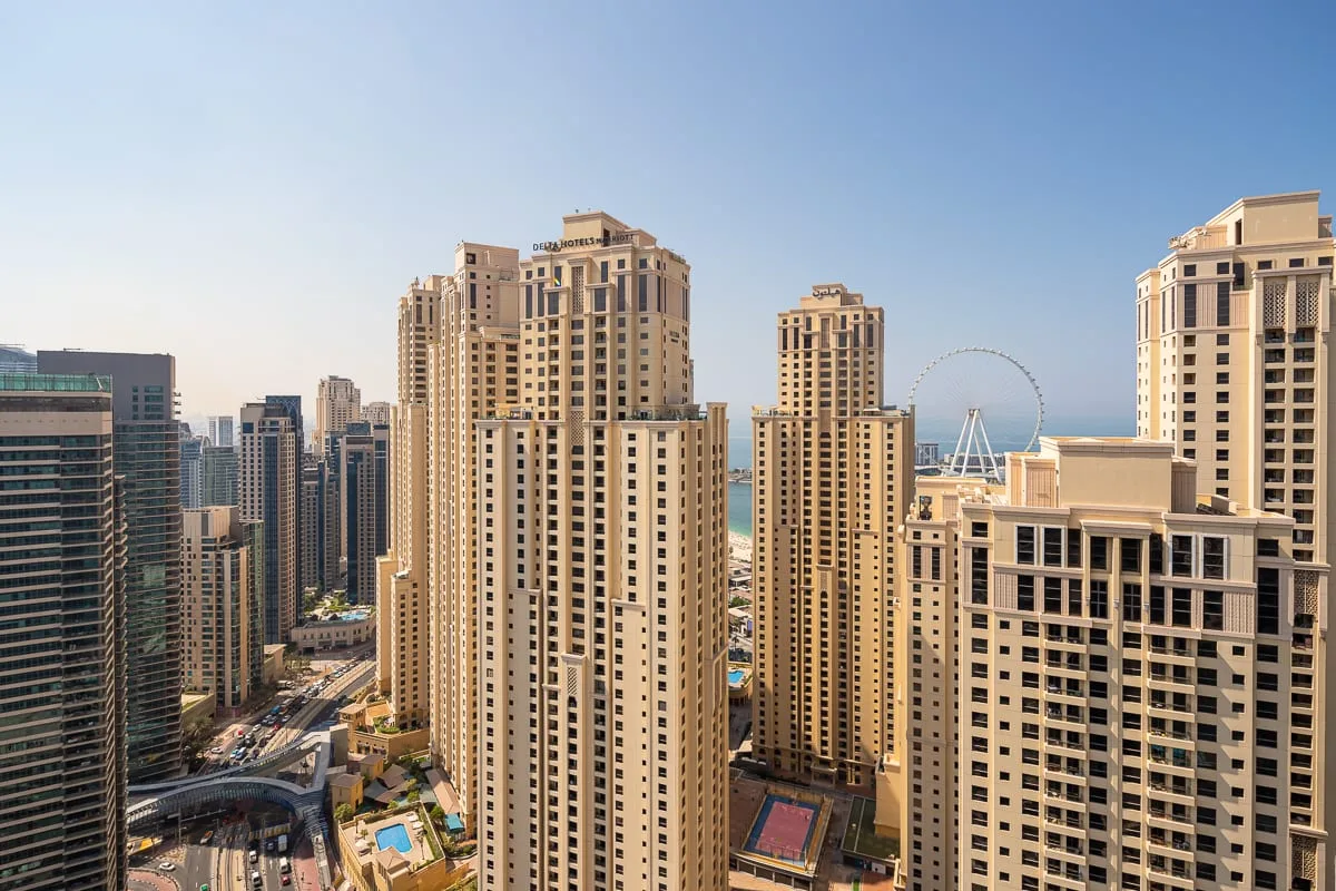 Un horizonte urbano de edificios altos con una gran noria a lo lejos.