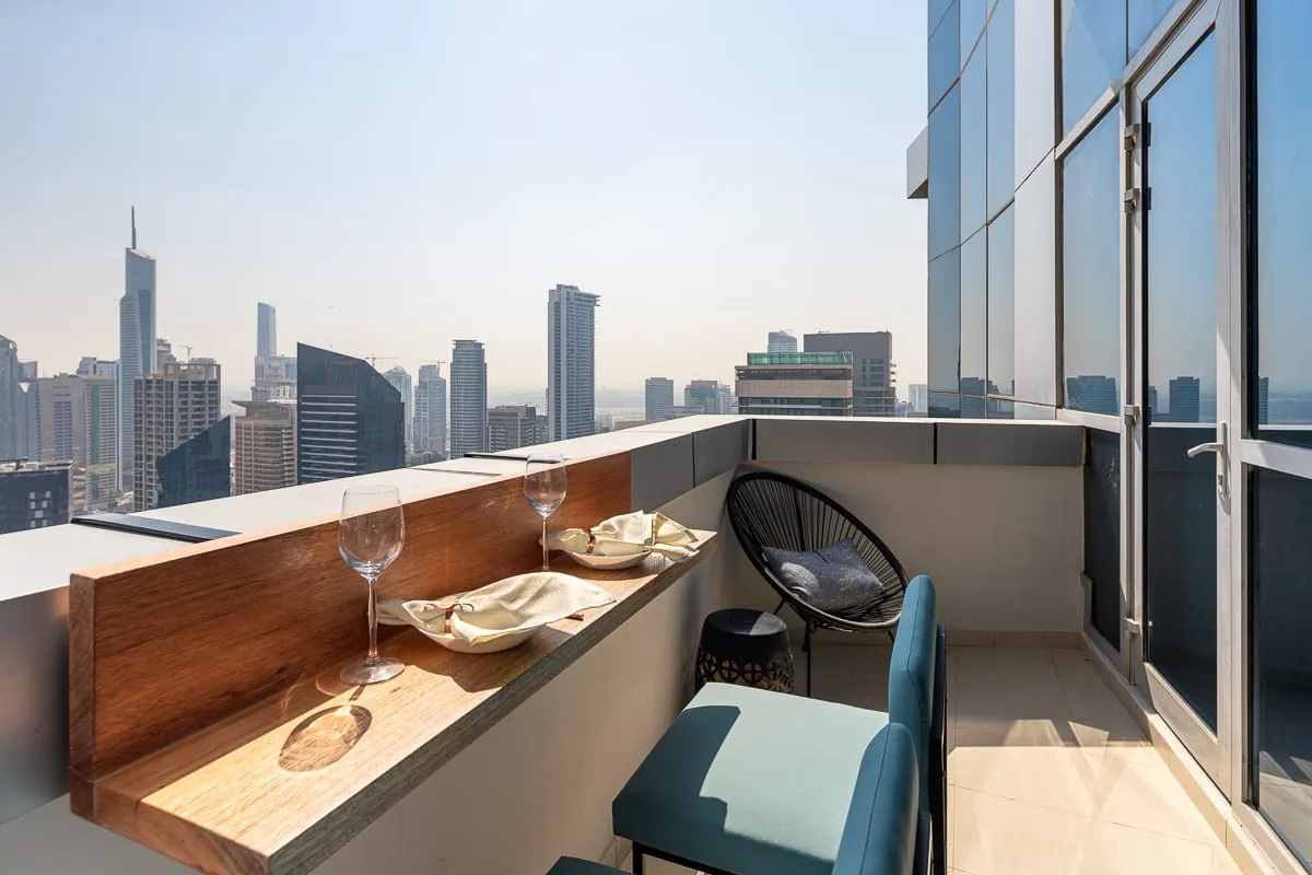 Una zona de estar en un balcón con vistas al horizonte urbano y una barra para comer.