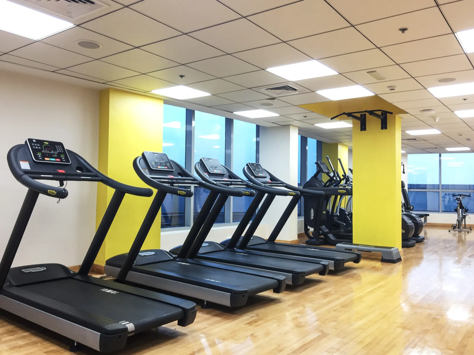 Una sala de entrenamiento con cintas de correr junto a grandes ventanas.