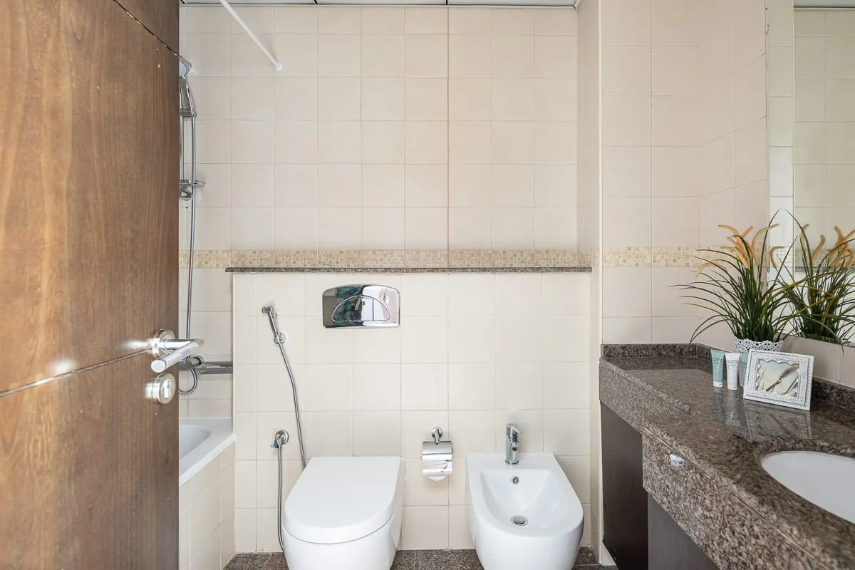 Un baño alicatado con ducha, inodoro y lavabo.