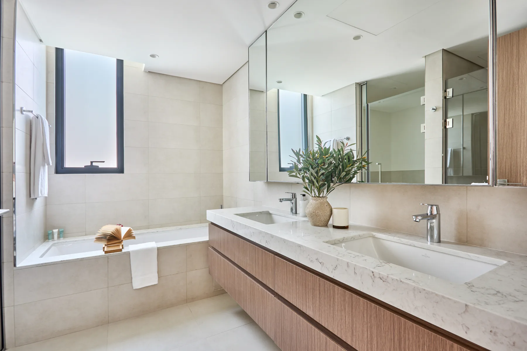 Un baño luminoso con bañera, lavabo doble y un espejo grande.
