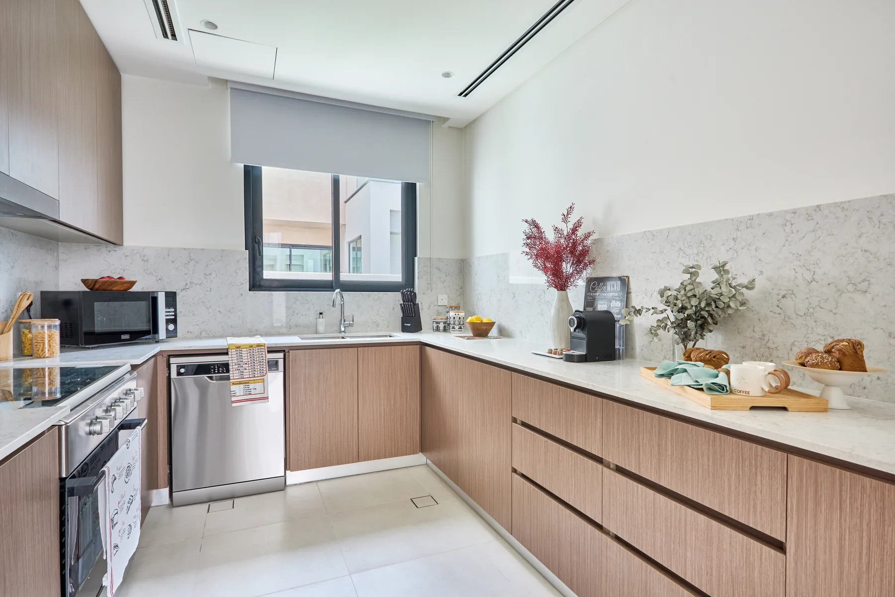 Una cocina moderna con gabinetes de madera, una encimera y una ventana sobre el fregadero.