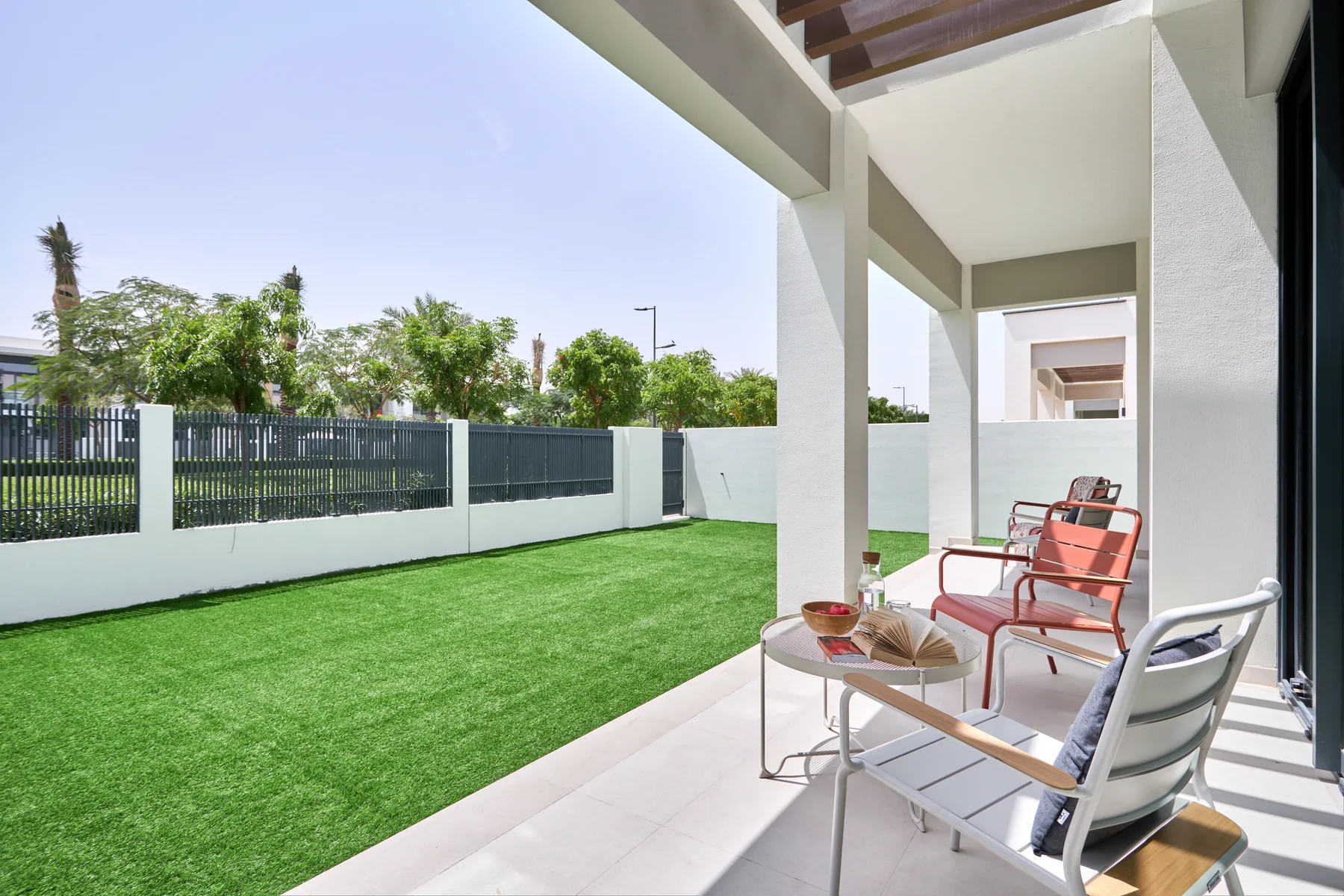 Un patio cubierto con asientos al aire libre da a un césped verde y una cerca.