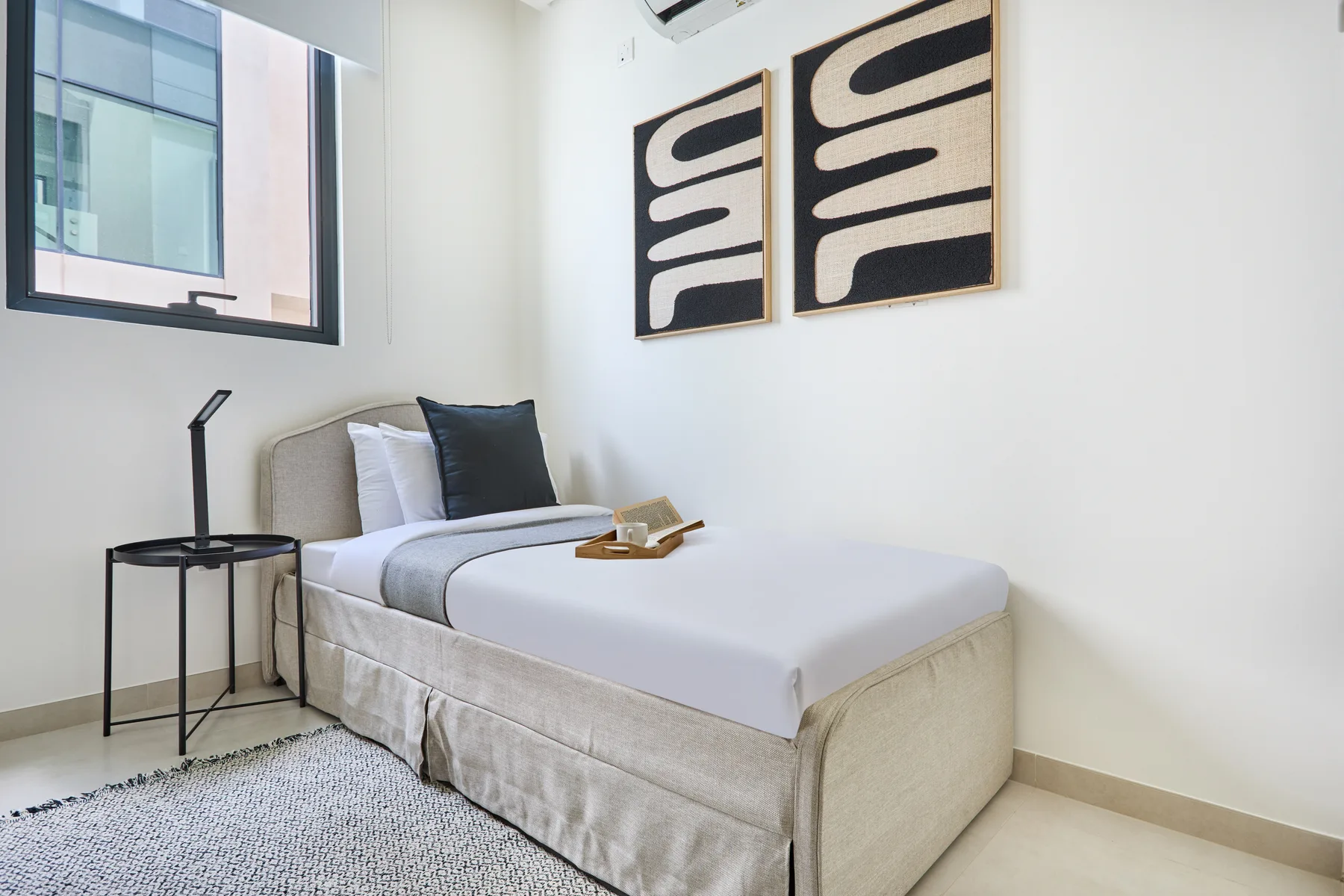 Un dormitorio con una cama bien arreglada y arte abstracto en la pared.