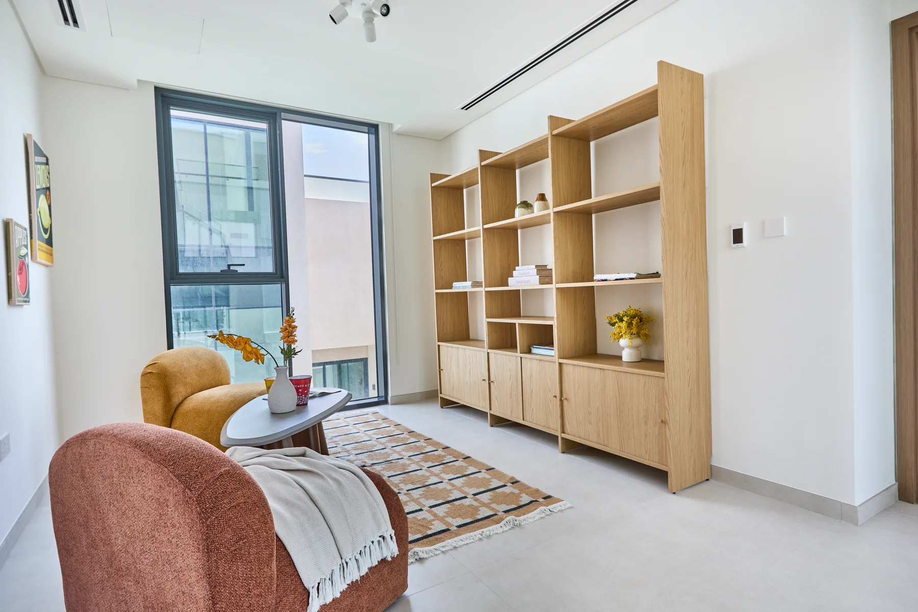 Una luminosa sala de estar con asientos, estanterías de madera y una ventana grande.