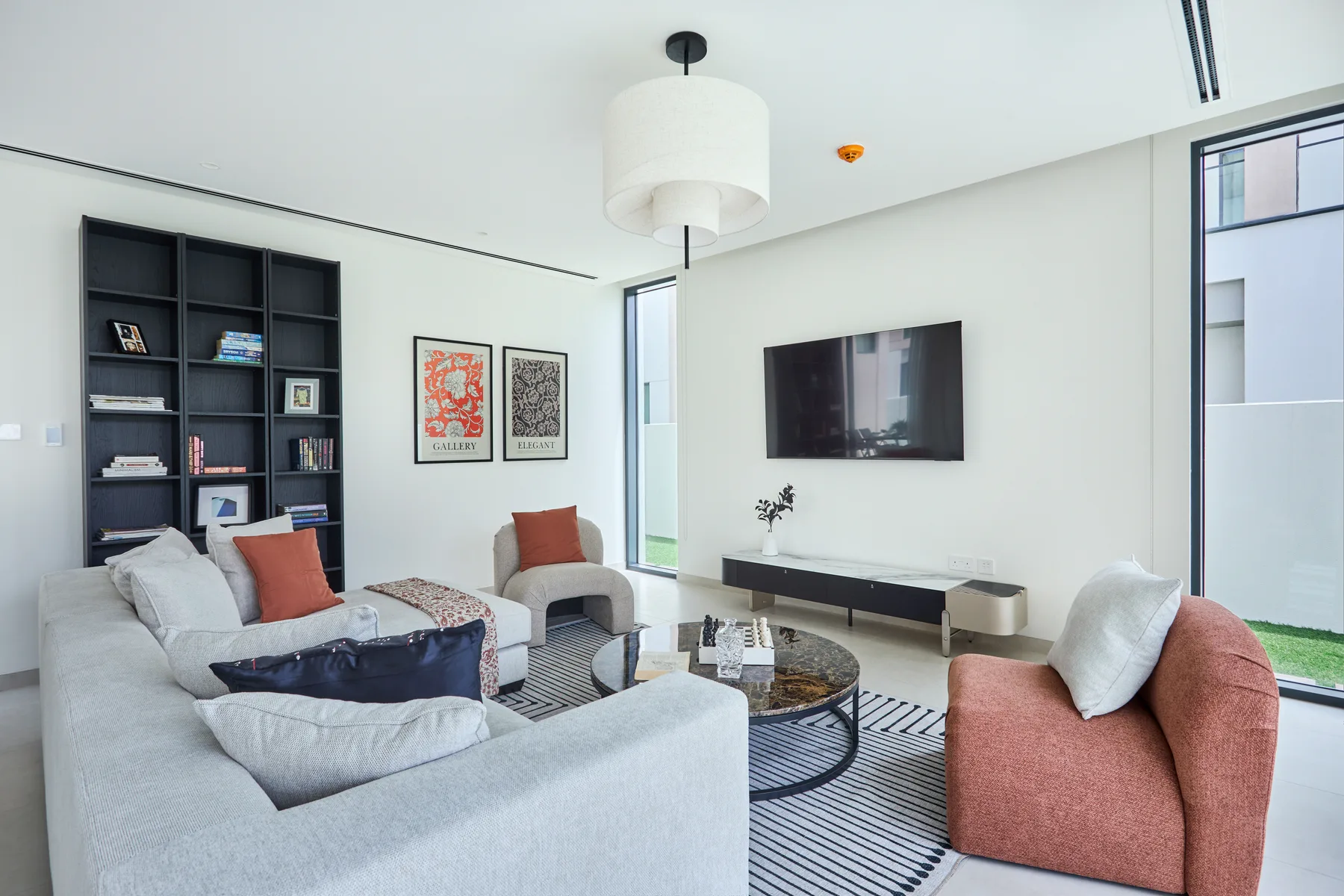 Una sala luminosa con asientos, una mesa de centro y un televisor montado en la pared.