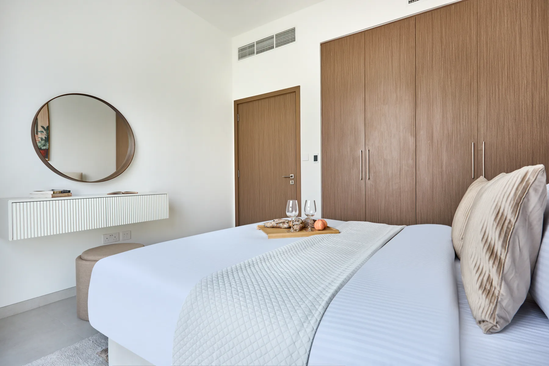 Un dormitorio con una cama bien hecha y armarios revestidos de madera.