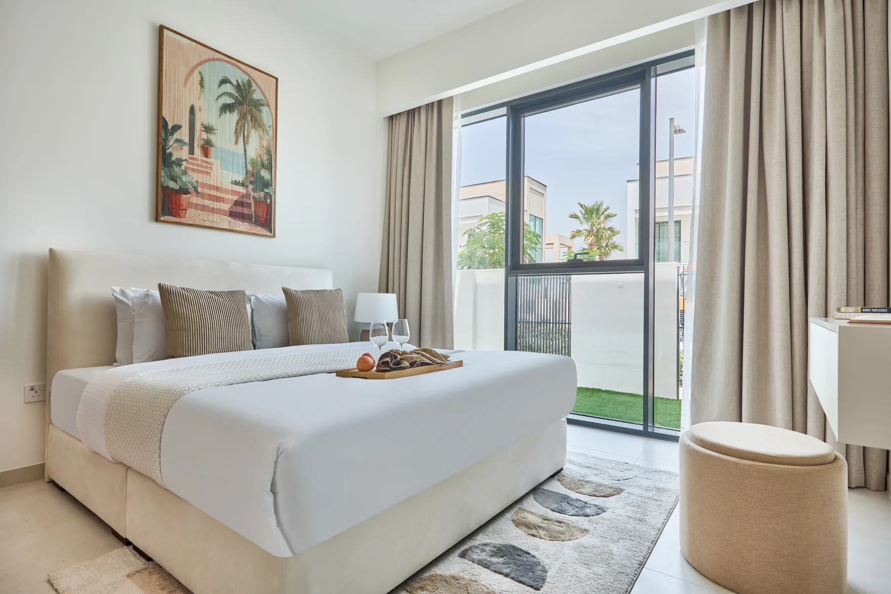Un dormitorio con una cama bien tendida junto a una ventana amplia.