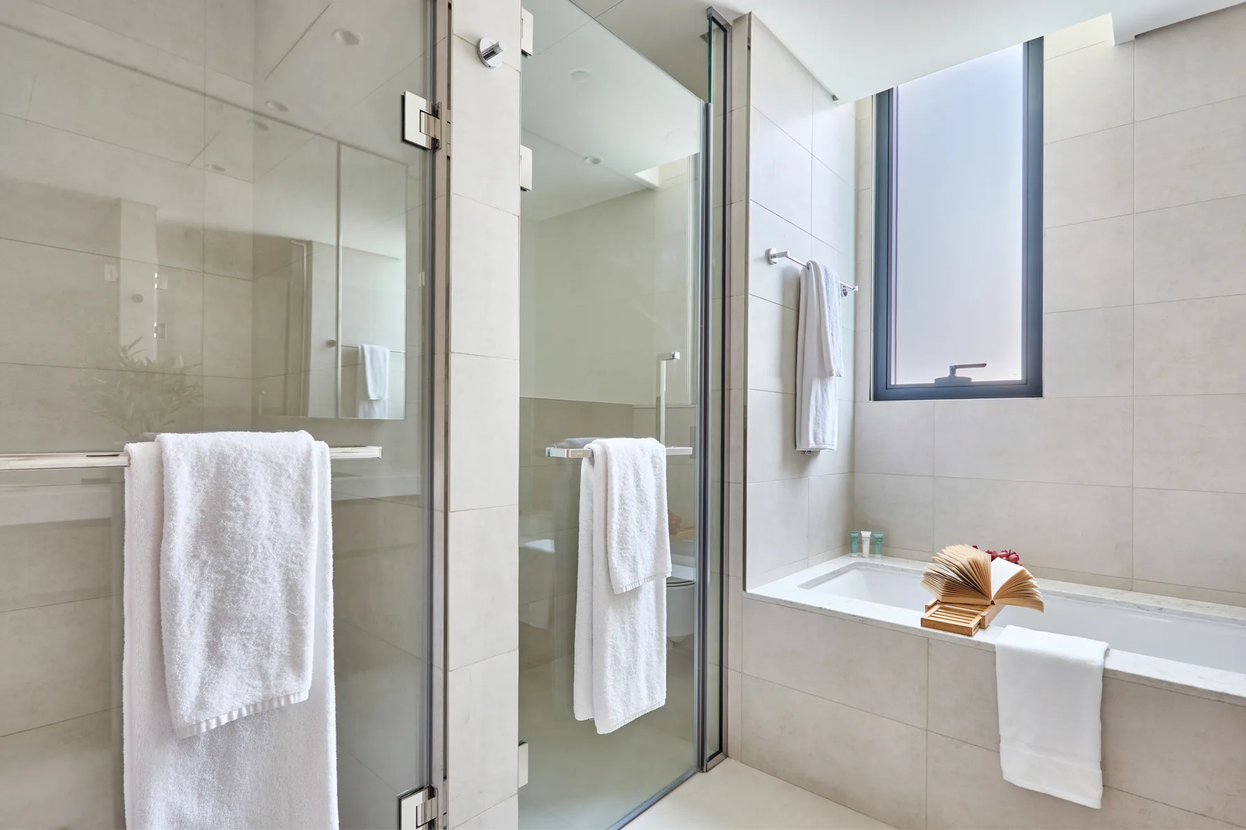 Un baño luminoso con una ducha de cristal y una bañera.