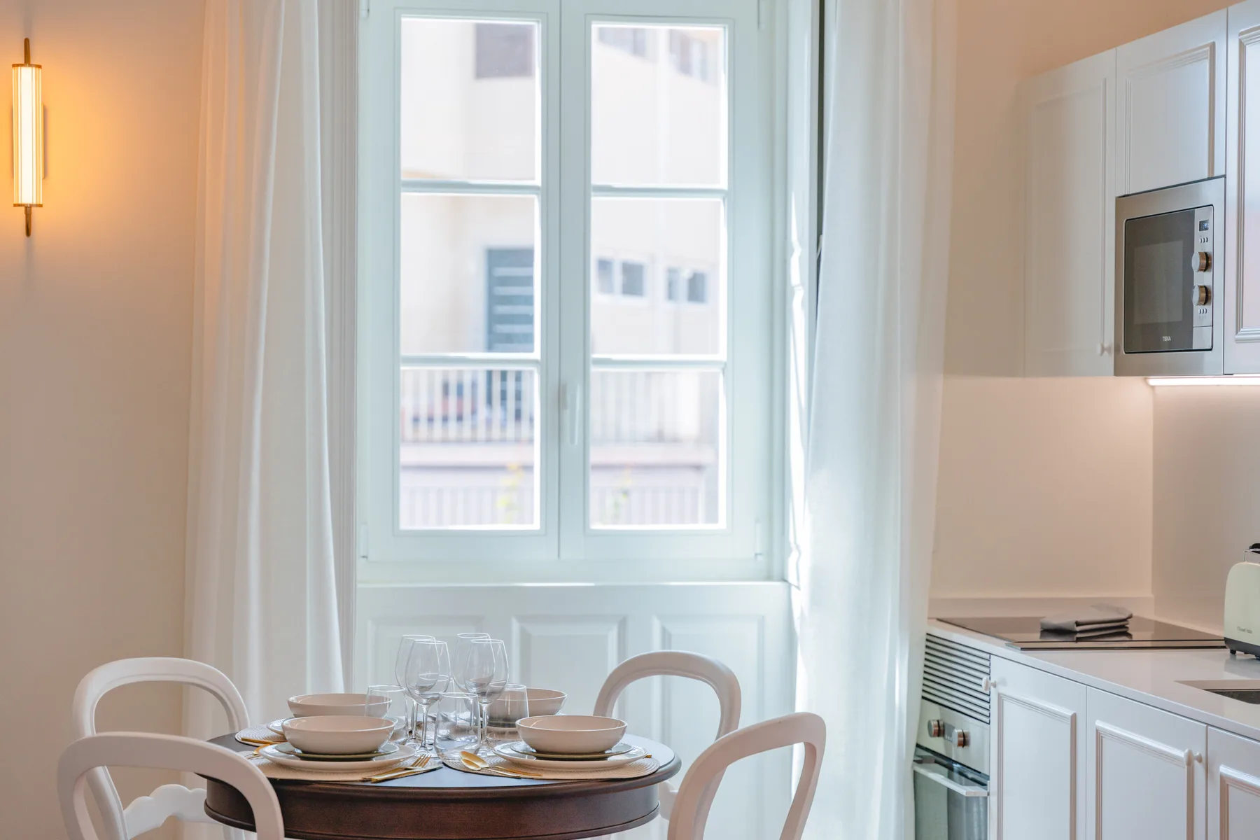 Comedor junto a la cocina, con una mesa redonda junto a una ventana amplia.
