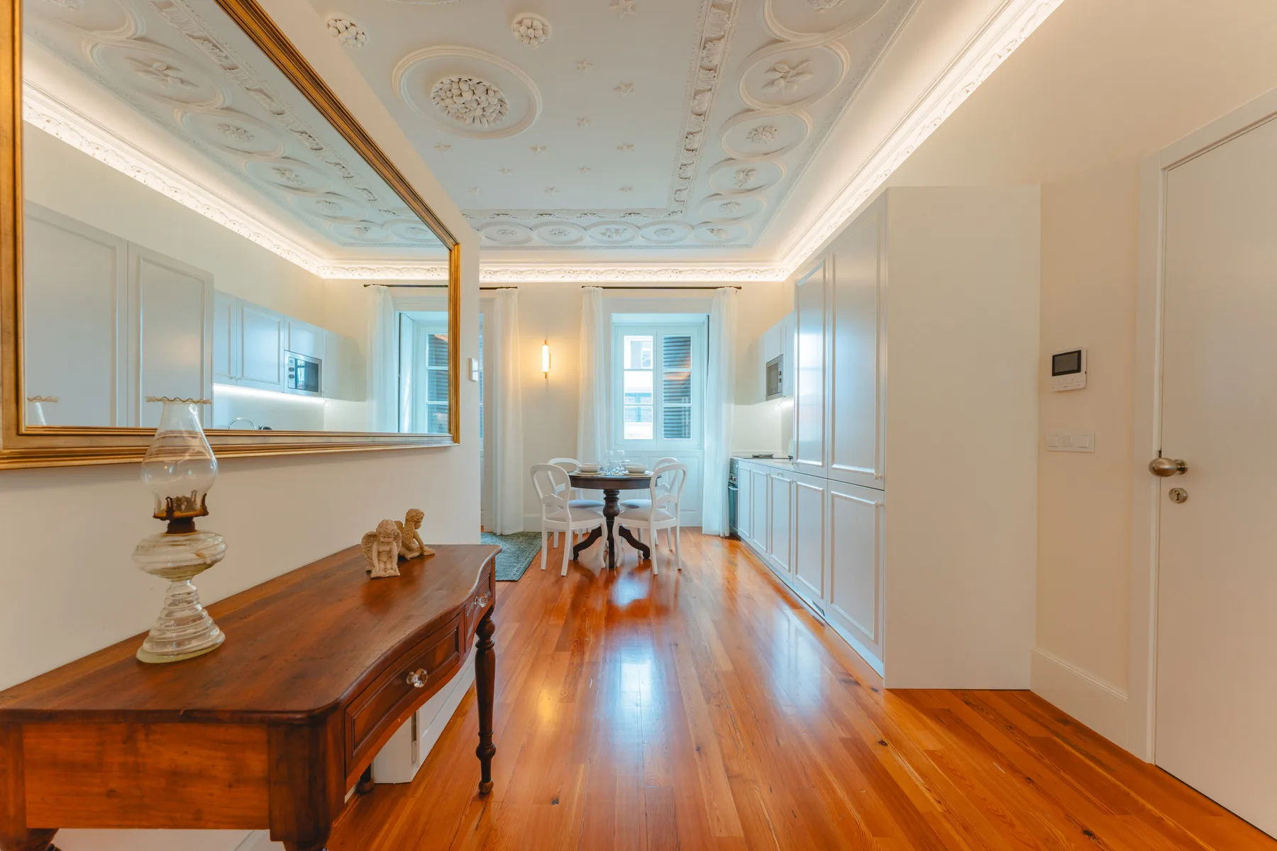 Un comedor luminoso con una mesa larga de madera, armarios claros y un techo decorativo.