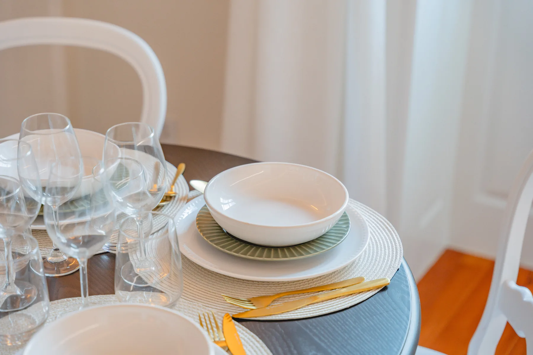 Una mesa de comedor está puesta con platos, cubiertos y cristalería.