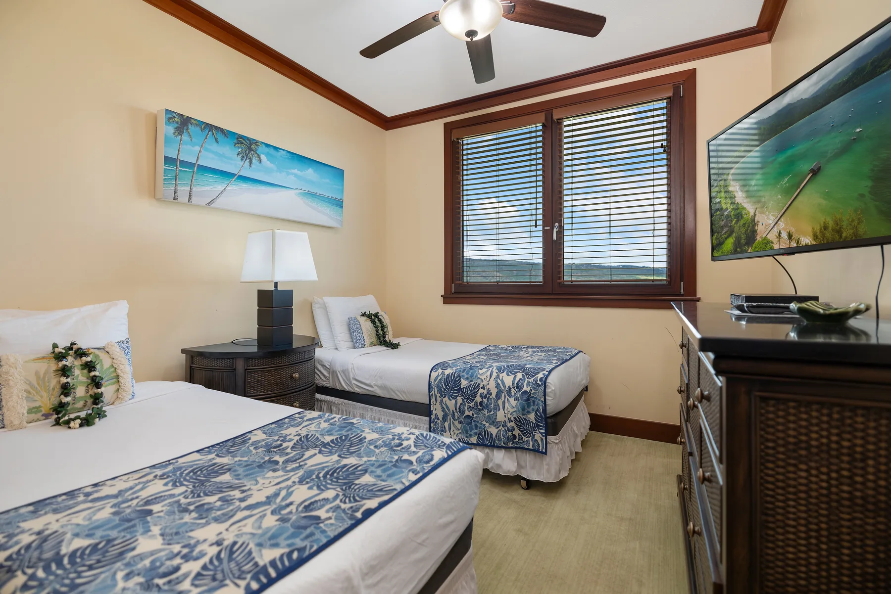 Un dormitorio con dos camas, ropa de cama azul estampada y una ventana con persianas.
