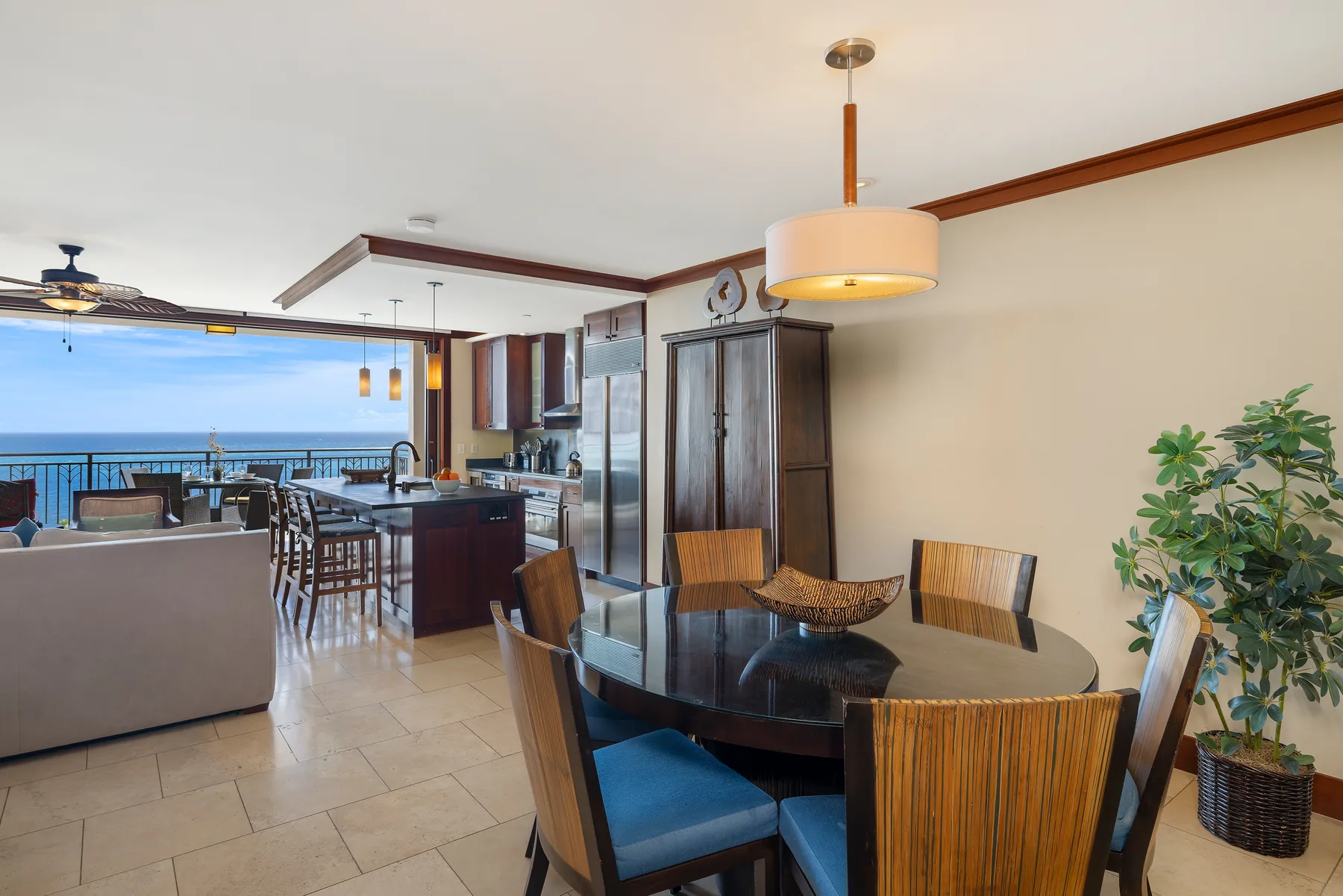 Una zona abierta de comedor y cocina tiene una mesa de vidrio y vistas al mar.